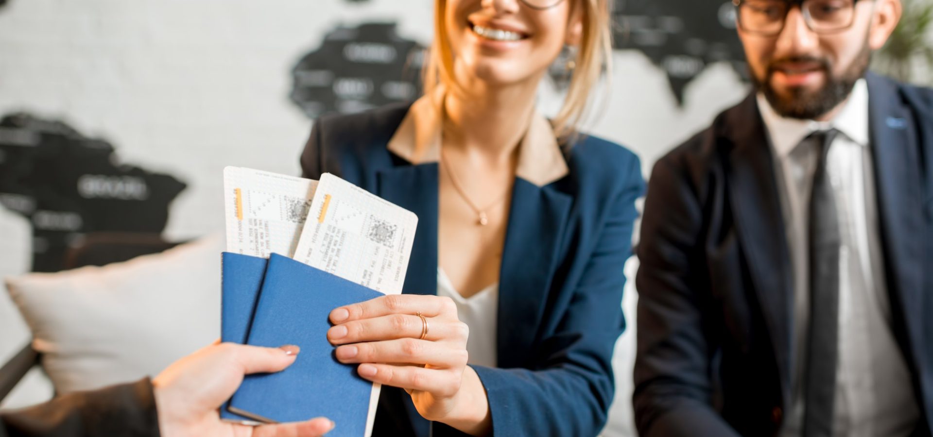 Young businesscouple choosing a trip with agent sitting at the travel agency office with world map on the background